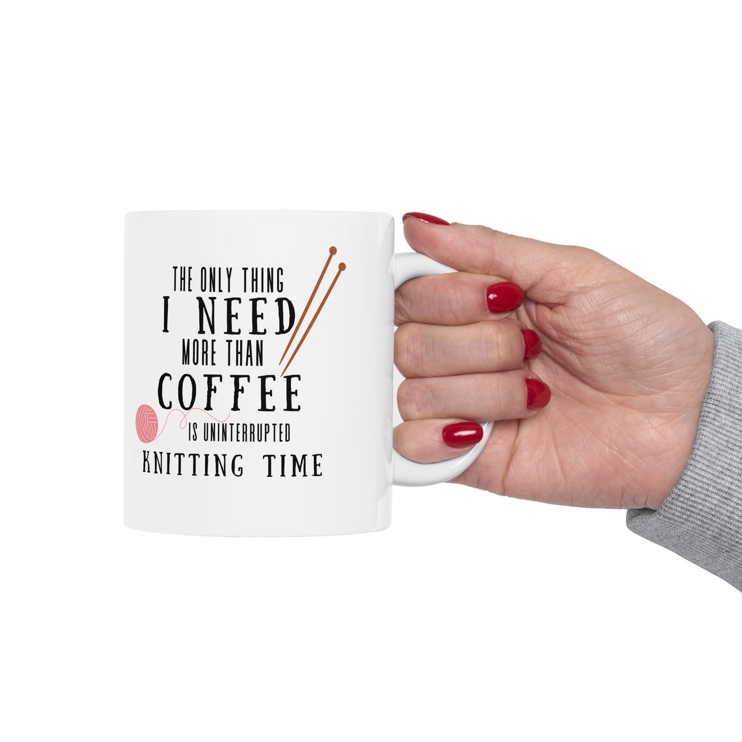 Hand holding a mug with text 'The only thing I need more than coffee is uninterrupted knitting time' on a white background