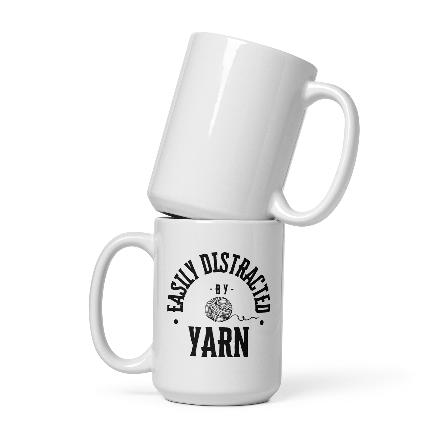 A white mug that says "Easily Distracted by Yarn" in black letters.