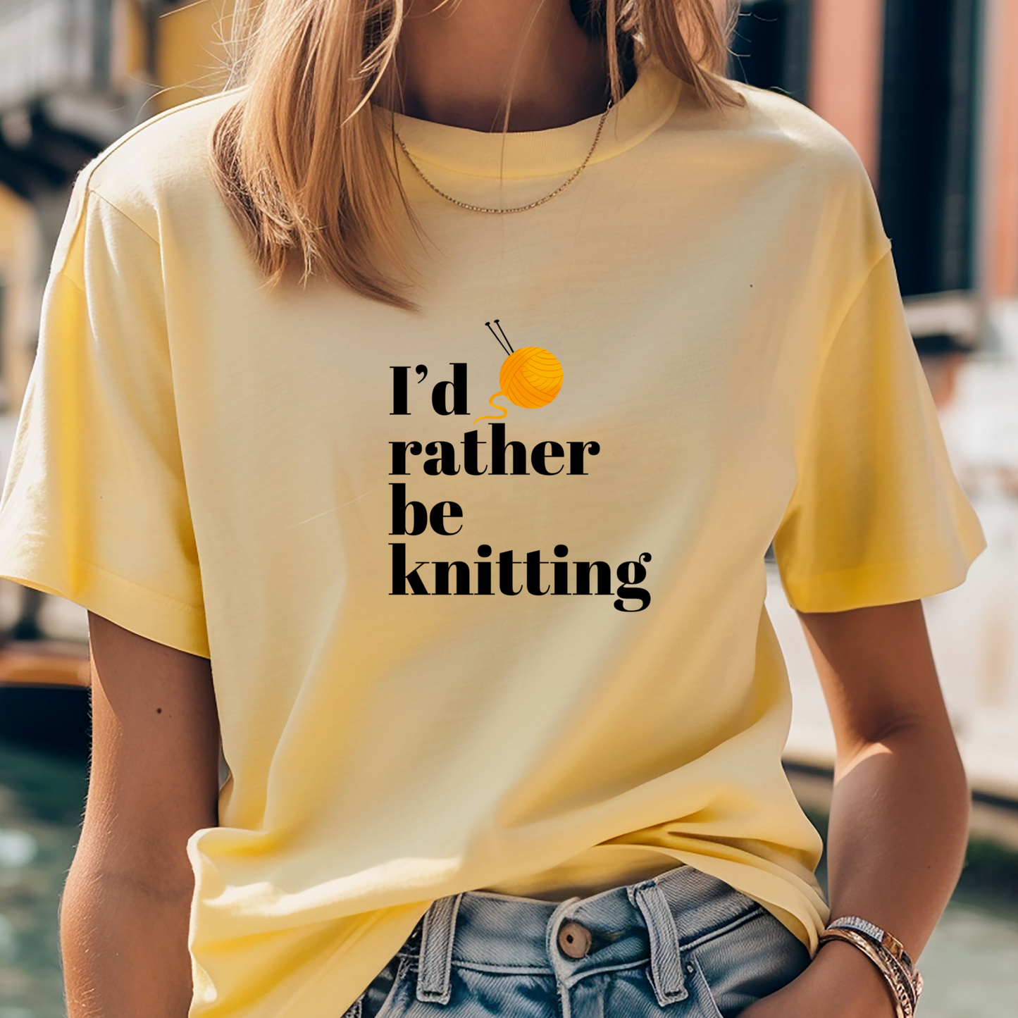 Person wearing a yellow t-shirt with 'I'd rather be knitting' text and an orange ball of yarn graphic.