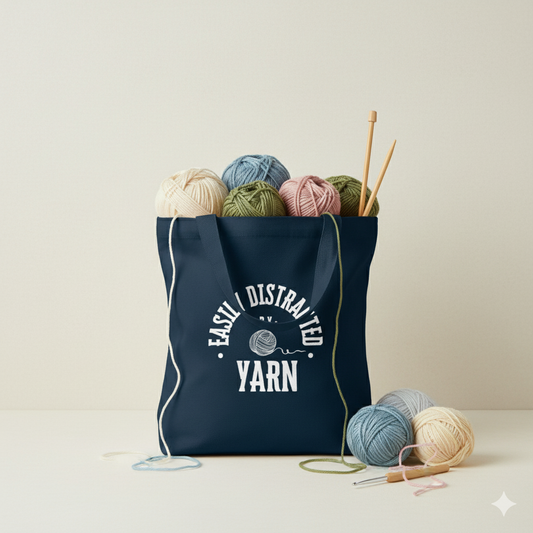 Navy tote bag with yarn and knitting needles on a light background